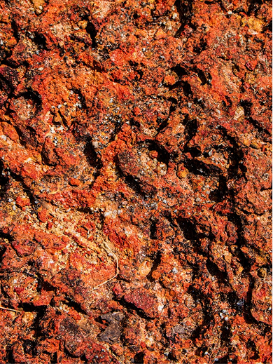 Richly textured plaster surface with deep red and black tones